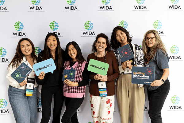 Six people pose for a photo in front of a WIDA backdrop.